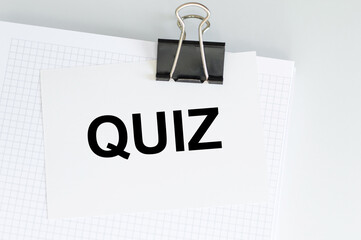 Quiz text on a card that is attached to white paper on a light background on a clip