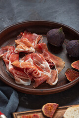 Jamon with figs and a baguette with cream cheese on the dining table, appetizer for wine, Spanish cooking.