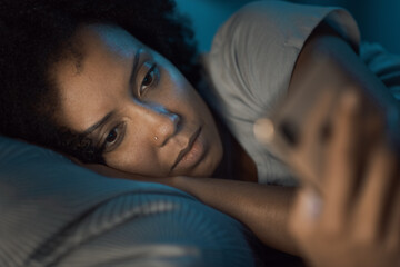 Sleepless woman connecting with her smartphone at night
