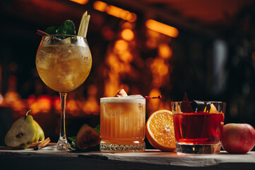 Three different beautiful cocktails in warm colors on a flower background