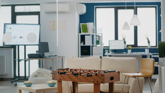 Nobody in business office with games to have fun after work. Empty workplace with chips, foosball table to play soccer game. Room used for entertainment with colleagues after hours.