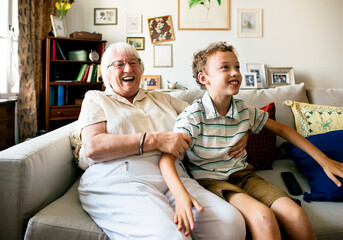 Grandma and grandson sitting on the sofa together - obrazy, fototapety, plakaty