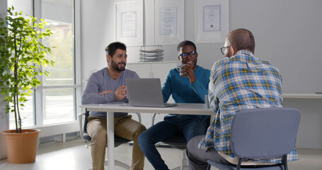 Young diverse colleagues enjoying coffee and talk working in office together
