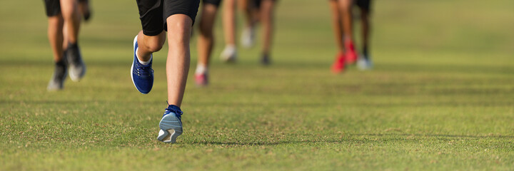 Fototapeta premium Running children, young athletes run in a kids run race, running on grass detail on legs, running in the light of morning