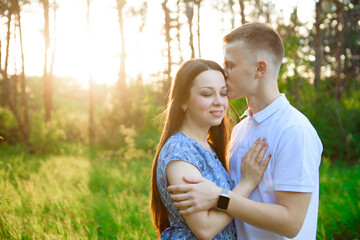Fototapeta premium Happy couple in love in springtime at sunset. Woman and man holding hands and hugging.