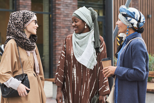 Three muslim women talking to each other and smiling during their meeting in the city