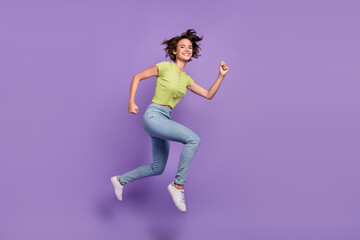 Fototapeta na wymiar Photo of pretty beautiful young lady wear green t-shirt smiling jumping high running fast isolated violet color background