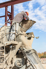 A worker on a concrete mixer truck prepares to concrete a reinforced concrete structure. Equipment...