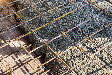 Pouring cement or concrete with a concrete mixer truck, construction site with a reinforced grillage foundation, start of construction of a production workshop.