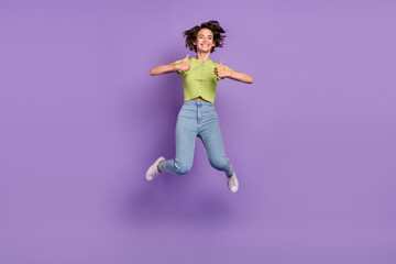 Photo of excited pretty young lady wear green t-shirt smiling jumping showing thumbs up isolated violet color background
