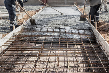 Pouring cement or concrete with a concrete mixer truck, construction site with a reinforced grillage foundation, start of construction of a production workshop. - obrazy, fototapety, plakaty