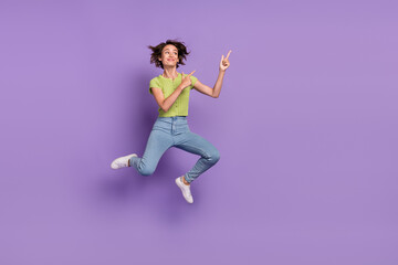 Fototapeta na wymiar Photo of dreamy charming young woman dressed green t-shirt jumping looking pointing fingers empty space isolated purple color background