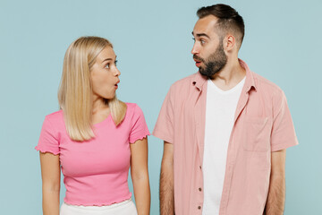 Fototapeta premium Young surprised shocked couple two friends family man woman in casual clothes look to each other together isolated on pastel plain light blue color background studio portrait People lifestyle concept.
