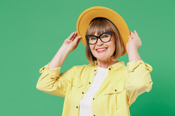 Elderly smiling happy fashionable woman 50s wearing glasses yellow shirt white t-shirt touch hat...