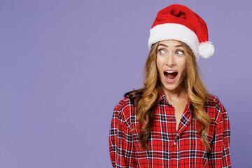 Shocked pop-eyed young Santa woman 30s wear shirt Christmas hat looking aside surprised isolated on plain pastel light violet background studio portrait. Happy New Year celebration holiday concept