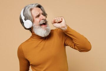 Elderly gray-haired mustache bearded man 50s in mustard yellow turtleneck shirt headphones listen...