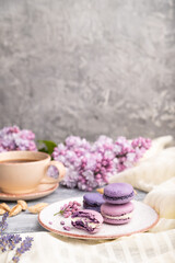 Obraz na płótnie Canvas Purple macarons or macaroons cakes with cup of coffee on a gray wooden background. Side view, copy space.