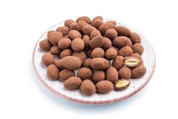 Almond in chocolate dragees on ceramic plate isolated on white background. Side view.
