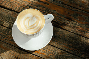 White cup of cappucino on the wooden rustic table. Top view. Natural style.