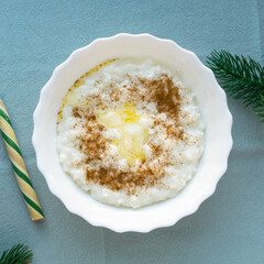 Christmas rice porridge with butter and cinnamon on blue textile background, top view