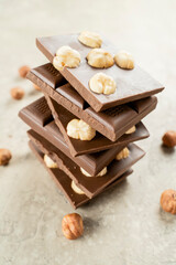 Tower of chocolate pieces with hazelnuts on a white background. Milk chocolate with nuts. Confectionery craft on table stack for Delicious Chocolate