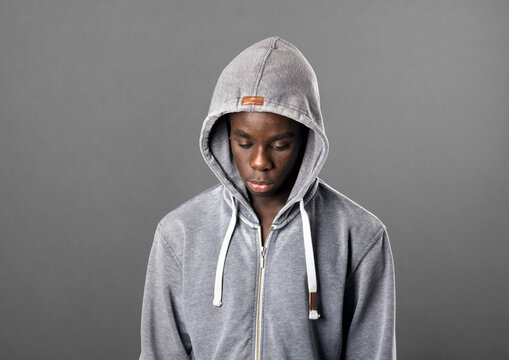 Young Black man wearing a grey hoodie looking down