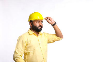 Young Indian engineer wearing yellow color hard hat on white background.