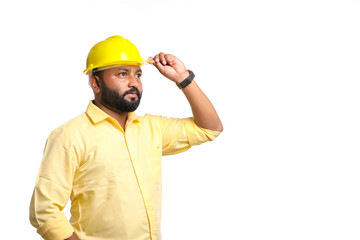 Young Indian engineer wearing yellow color hard hat on white background.