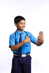 Indian little boy in school uniform with stethoscope and using smartphone on white background.