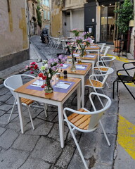 Tables mises fleuries dans la rue. Longue terrasse de restaurant dans une rue étroite.