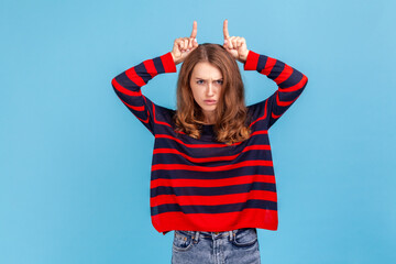 Woman showing bull horn gesture and looking with hate rage at camera, threatening and provoking...