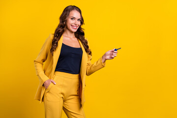 Photo of beautiful attractive young lady wear suit jacket pointing key empty space smiling isolated yellow color background
