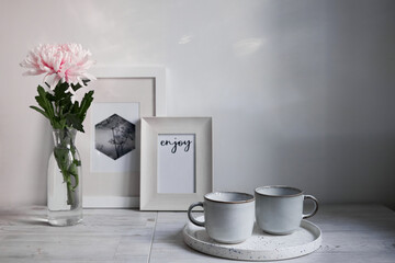 Scandinavian style. Interior Design. Large pink chrysanthemum in a long glass vase. Two cups of different size. Frame for photo. Empty space for text