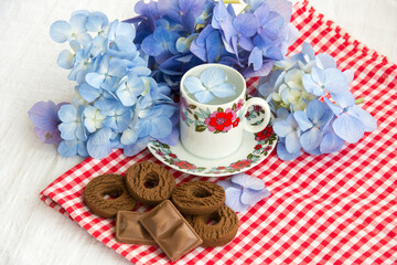 cup of tea on the table with hydrangea flowers around