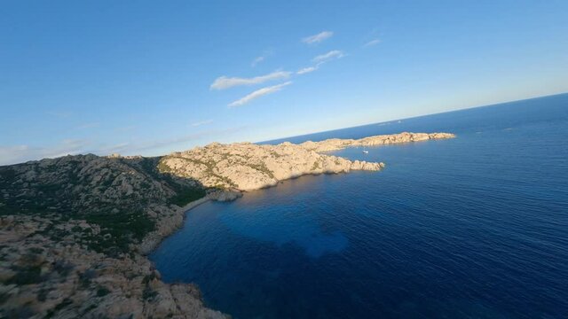 FPV video, flying at high speed over a granite coast with a turquoise bay of water. Cala Coticcio (Tahiti) La Maddalena archipelago, Sardinia, Italy.