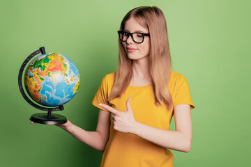 Portrait of pretty charming lady indicate finger globe choose country wear eyeglasses yellow t-shirt