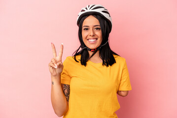 Young caucasian woman with one arm wearing a bike helmet isolated on pink background showing number two with fingers.