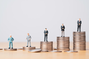 Different miniature businessman standing on different height coins stacking , Inequality income and...