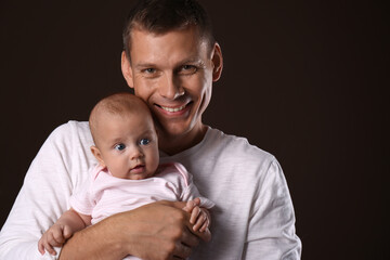 Happy father with his little baby on dark background