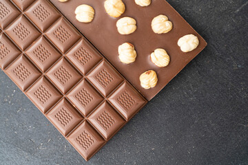 Milk chocolate with hazelnuts on black background. Handmade organic chocolate with nuts for candy store
