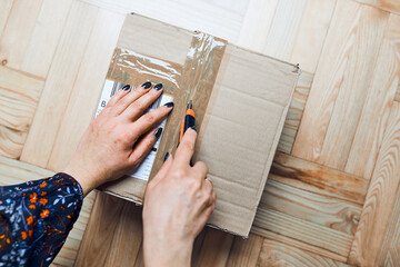 Woman opening parcel online order. Unpacking box with ordered items