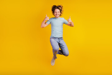 Fototapeta na wymiar Full-body photo of young excited man happy positive smile jump thumbs-up fine ad cool feedback isolated on shine yellow background