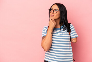 Young caucasian student woman with one arm isolated on pink background looking sideways with doubtful and skeptical expression.