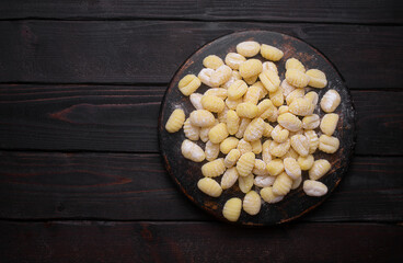 Raw italian gnocchi on a dark background prepared with potato and dough