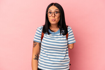 Young caucasian student woman with one arm isolated on pink background shrugs shoulders and open eyes confused.