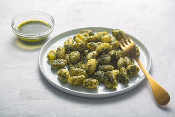 Traditional gnocchi with pesto sauce on gray concrete background. It usually prepared with potato and dough