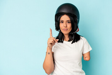 Young caucasian woman with one arm wearing a motorcycle helmet isolated o blue background showing number one with finger.