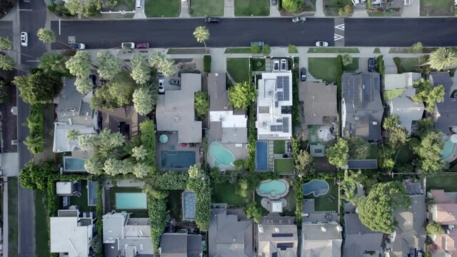 Birdseye aerial view above Van Nuys residential homes rooftops streets pools and property gardens