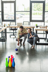 Happy interracial business people playing bowling in office