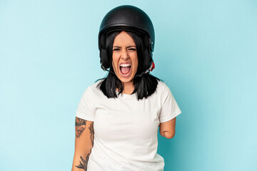 Young caucasian woman with one arm wearing a motorcycle helmet isolated o blue background screaming very angry and aggressive.